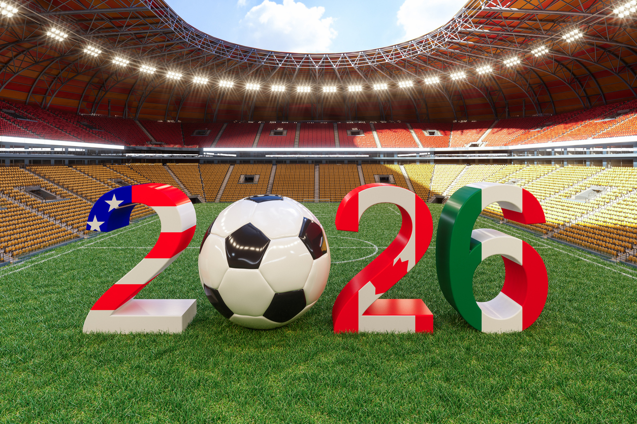 Soccer ball placed between the numbers 2026 on a football field inside a modern stadium, symbolizing the 2026 international tournament